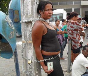 Imagem Em protesto, mulher se acorrenta em frente à hospital